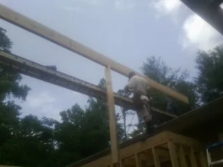 Carpenter setting a ridge beam over a new addition frame — Ice Dam Removal by Roofing Brothers in Biscoe