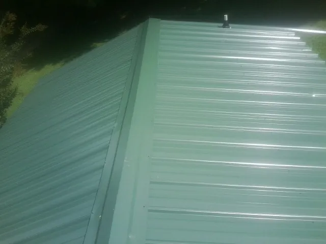 New green metal panels meeting at the ridge of a roof — Flat Roof Repair work by our crew in Biscoe