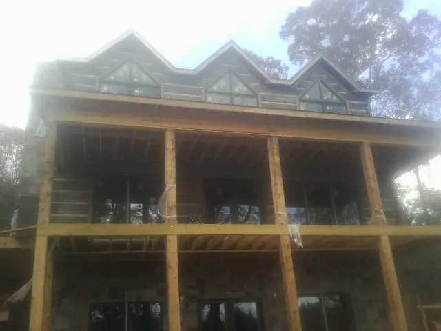 Dormers and porch framing on a large log home under construction — Roof Coating work by our crew in Biscoe