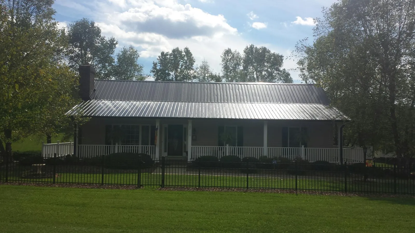 Gray metal roof on a brick ranch with a full width front porch — Gutter Guard Installation work by our crew in Biscoe